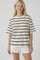 woman wearing a white striped t-shirt with green, red, and orange lines, paired with white shorts