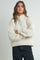 woman wearing a cream-colored fleece pullover with a snap collar and relaxed fit, standing with arms crossed