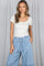 woman wearing a white short sleeve top with a scalloped neckline and blue polka dot drawstring shorts
