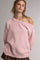 woman wearing a soft pink off-shoulder sweater with a relaxed fit and ribbed hem