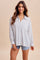 woman wearing a white and navy striped oversized button-up shirt with a chest pocket and blue denim shorts