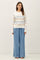 woman wearing a cream striped sweater with a pocket and light blue wide-leg pants