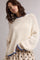 woman wearing a cream knitted sweater with blue trim and diamond texture, styled with a polka dot skirt
