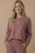 woman wearing a maroon and white striped long sleeve top with pockets and matching bottoms, smiling at the camera