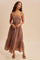 woman wearing a brown polka dot maxi dress with a square neckline and a tiered skirt