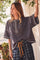 woman wearing a charcoal gray oversized henley shirt with buttons and relaxed fit, paired with checkered pants
