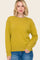 woman wearing a mustard yellow oversized sweater with long sleeves and a crew neckline