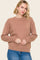 woman wearing a beige oversized sweater with a crew neckline and long sleeves, paired with blue jeans