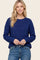 woman wearing a navy blue textured knit sweater with a relaxed fit and long sleeves, paired with light blue jeans