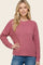 woman wearing a pink textured long sleeve sweater with a relaxed fit and crew neckline, styled with blue jeans