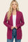 woman wearing a fuchsia long sleeve cardigan with pockets and a white top paired with blue jeans