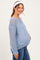 woman wearing a light blue maternity sweater with a relaxed fit and open knit pattern, showing her baby bump