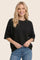 woman wearing a black oversized short sleeve sweater with a round neckline and relaxed fit paired with light blue jeans