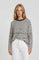 woman wearing a striped cream and black oversized sweater with a relaxed fit and long sleeves, paired with white pants