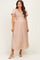 woman wearing a beige polka dot maternity dress with short puff sleeves and a smocked bodice