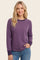 woman wearing a purple long sleeve sweatshirt with a relaxed fit and darker purple cuff details, smiling at the camera