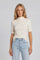 woman wearing a cream short sleeve mock neck top with a fitted style and light blue high-waisted jeans