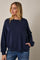 woman wearing a navy oversized sweatshirt with a round neckline and a front pocket, styled with casual jeans