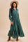 woman wearing a green maxi dress with long sleeves and button details, styled with a wide-brimmed hat and brown boots