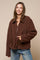 woman wearing a brown zip-up fleece jacket with large pockets and a collared neckline, styled with blue jeans