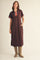 woman wearing a brown midi dress with a collar and striped details, paired with tan cowboy boots and standing with hands in pockets