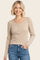 woman wearing a beige striped long sleeve henley top with button details and a round neckline, paired with blue jeans