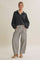 woman wearing a black quarter-zip pullover and gray striped wide-leg pants with pockets, standing in beige heels