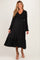 woman wearing a black maternity dress with puffed sleeves and a ruffled hem, showcasing her baby bump