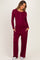 woman wearing a burgundy long sleeve maternity top with buttons and matching wide-leg maternity pants, showing her baby bump