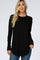 woman wearing a black long sleeve waffle knit top with a curved hem and relaxed fit, paired with blue jeans