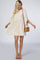 woman wearing a light beige swing dress with ruffled sleeves and a frayed hem, holding a small woven handbag
