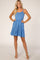 woman wearing a blue sleeveless sundress with a tiered ruffled skirt and strappy sandals