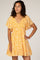woman wearing a yellow floral print short dress with v-neck and flutter sleeves