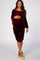 woman wearing a burgundy velvet maternity dress with long bell sleeves and gathered detailing, showing her baby bump
