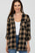 woman wearing a black and tan plaid flannel shirt over a white tank top with rolled-up sleeves and blue jeans