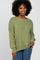 woman wearing a light olive green oversized sweater with a boat neckline and fitted ribbed cuffs