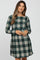 woman wearing a green and gray plaid maternity dress with long sleeves and a fitted waist, showing her baby bump