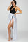 woman wearing a black maternity swimsuit with a sheer white cover-up tied at the waist and posing with a smile
