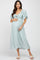 woman wearing a light blue maternity dress with flutter sleeves and a knotted front, cradling her baby bump