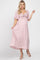 woman wearing a light pink maternity maxi dress with short flutter sleeves and a tie front, showing her baby bump