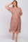 woman wearing a blush pink floral maternity dress with a pleated skirt and short sleeves, gently cradling her baby bump