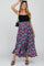 woman wearing a black tank top and a purple floral maxi skirt with a black shoulder bag