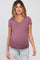 woman wearing a dusty mauve short sleeve maternity top with ruching and a visible baby bump, styled with distressed jeans