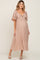 woman wearing a blush pink maternity dress with a tie front detail and flowing sleeves, highlighting her baby bump