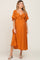 woman wearing an orange maternity dress with a tied front and flutter sleeves, showcasing her baby bump