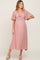 woman wearing a pink maternity maxi dress with a tied front detail and flutter sleeves, showcasing her baby bump