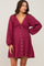 woman wearing a burgundy maternity dress with crochet detailing, long sleeves, and button closure, showing her baby bump