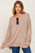 woman wearing a beige oversized sweater with a wide neckline and long sleeves, paired with blue jeans