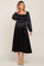 woman wearing a black maternity dress with a smocked bodice and long puff sleeves, showcasing her baby bump