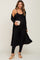 woman wearing a black ribbed maternity jumpsuit with a matching long cardigan and holding a clutch, showing baby bump